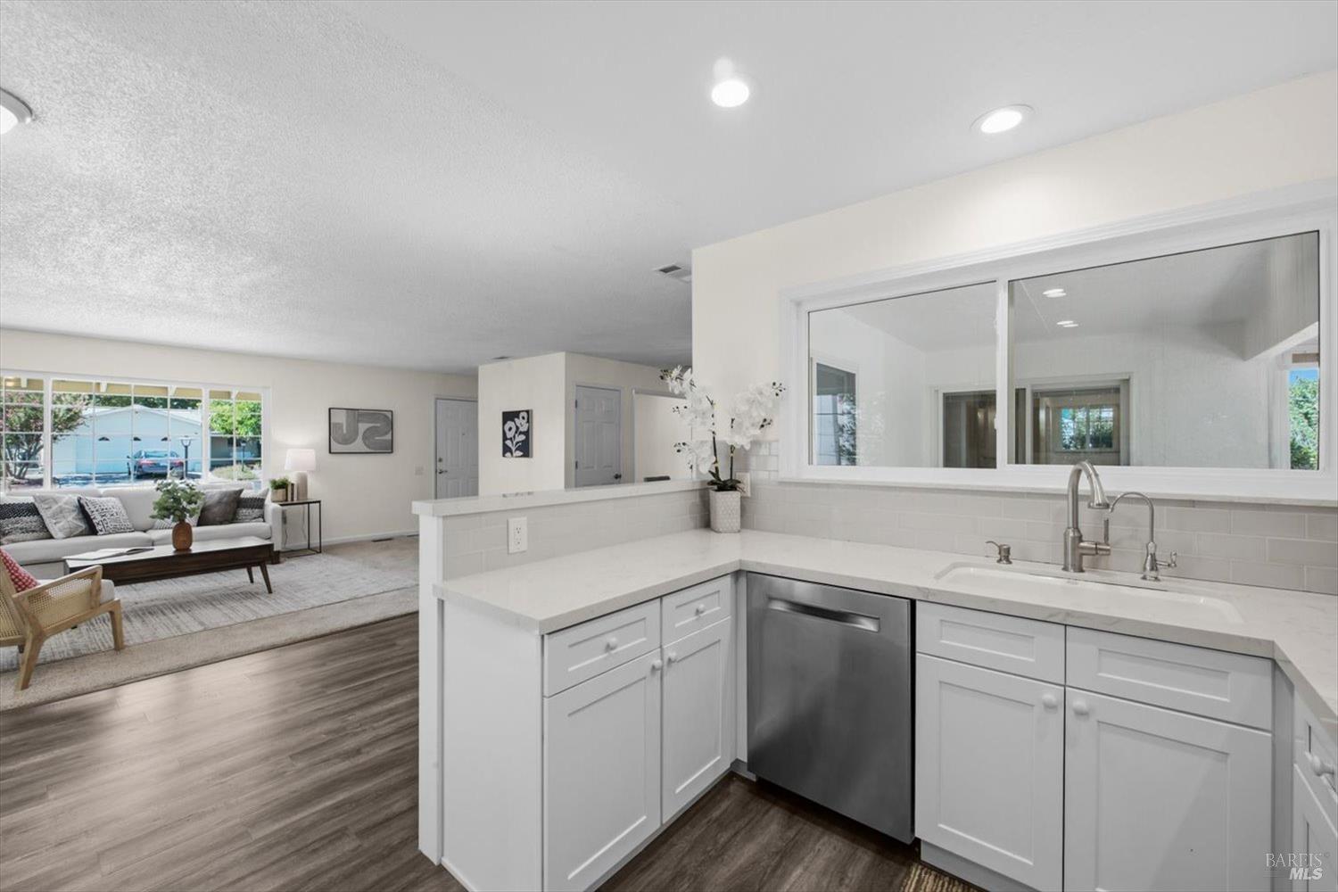Kitchen with white cabinets and a pass-through window overlooking the living room.