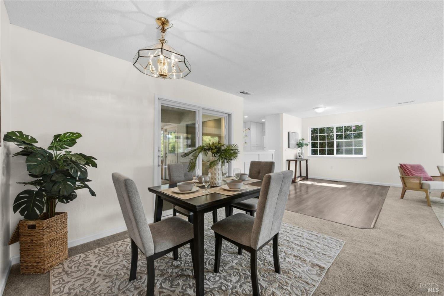 Dining area with a dark table and gray chairs opens into a bright living room.