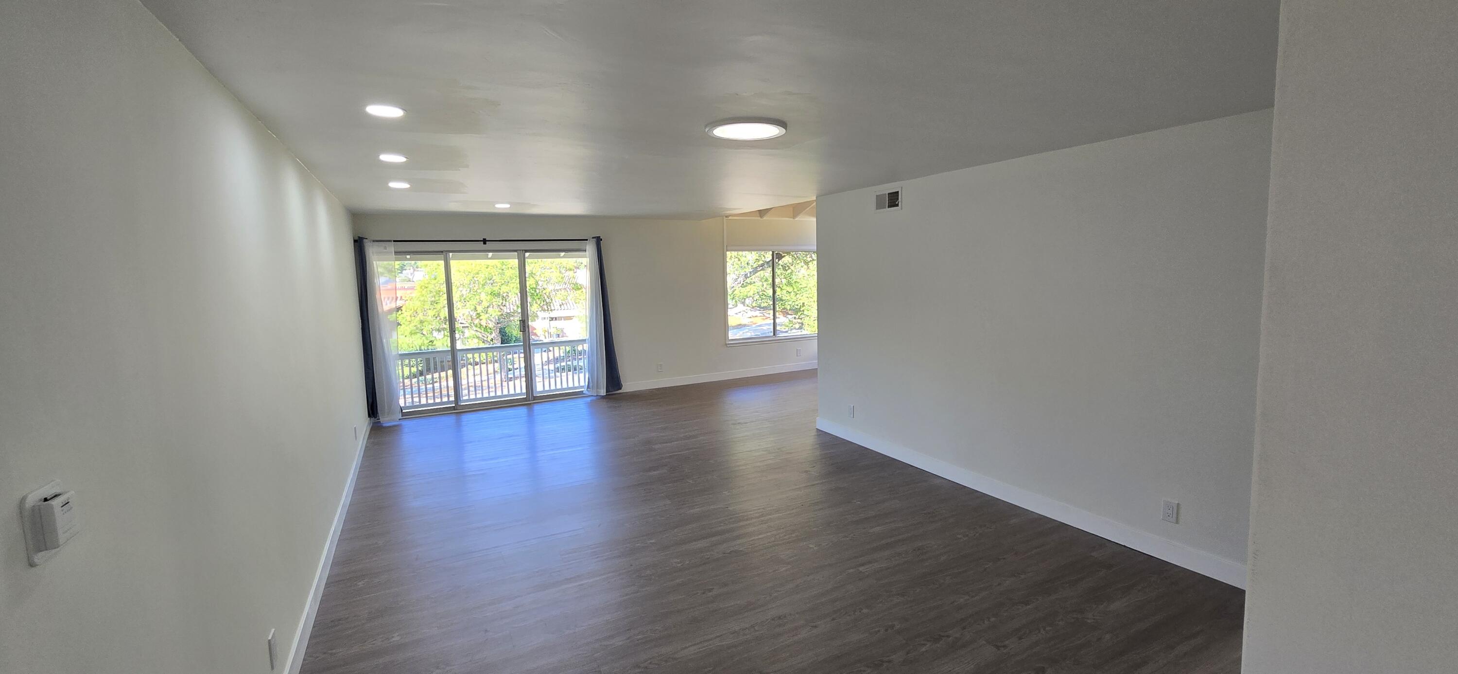 Vacant living room with dark flooring and sliding glass doors to a balcony.