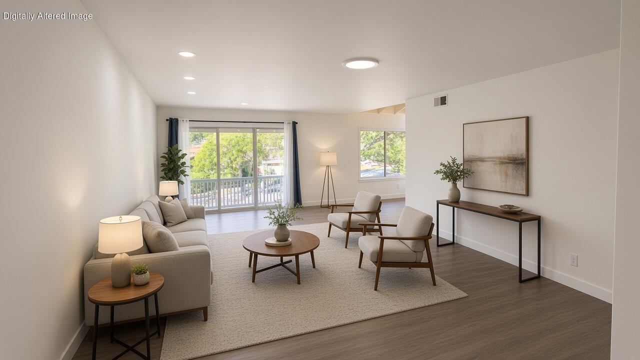 Staged living room with a beige sofa, armchairs, and sliding glass doors opening onto a balcony.