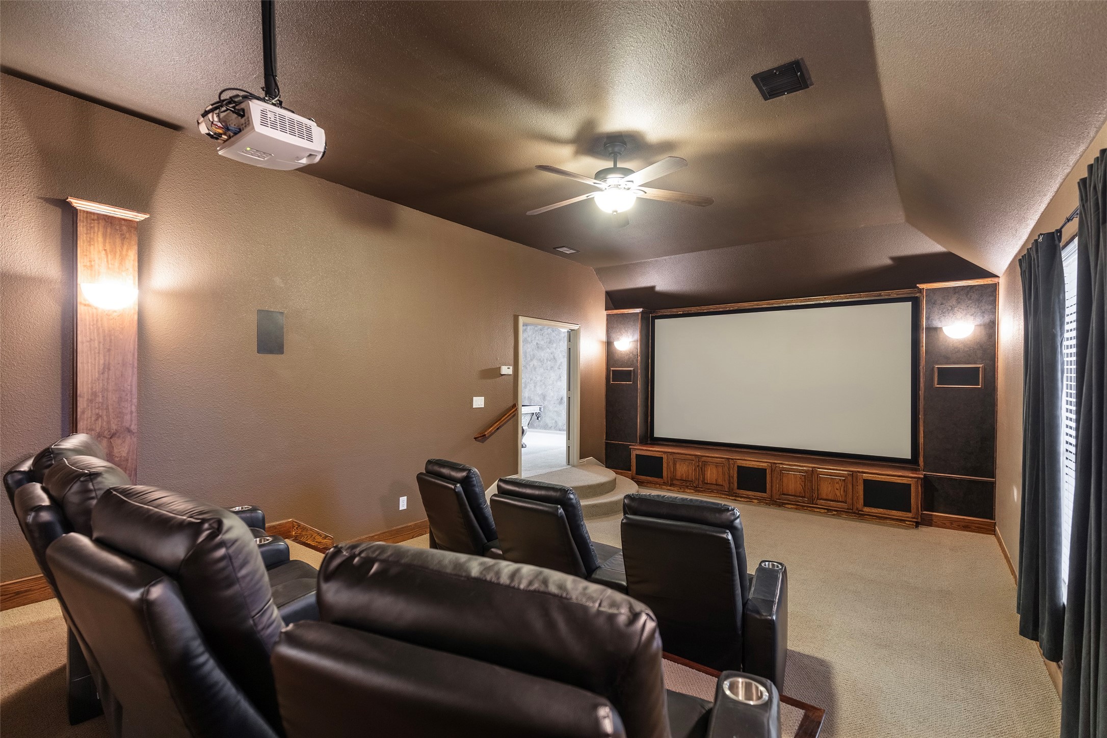 Home theater with black leather recliners, a large projection screen, and a ceiling-mounted projector.