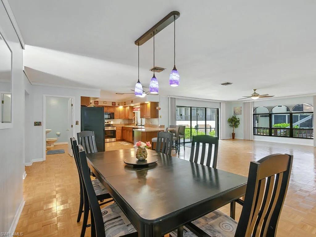 Dining room with dark wood table, pendant lights, and open kitchen.