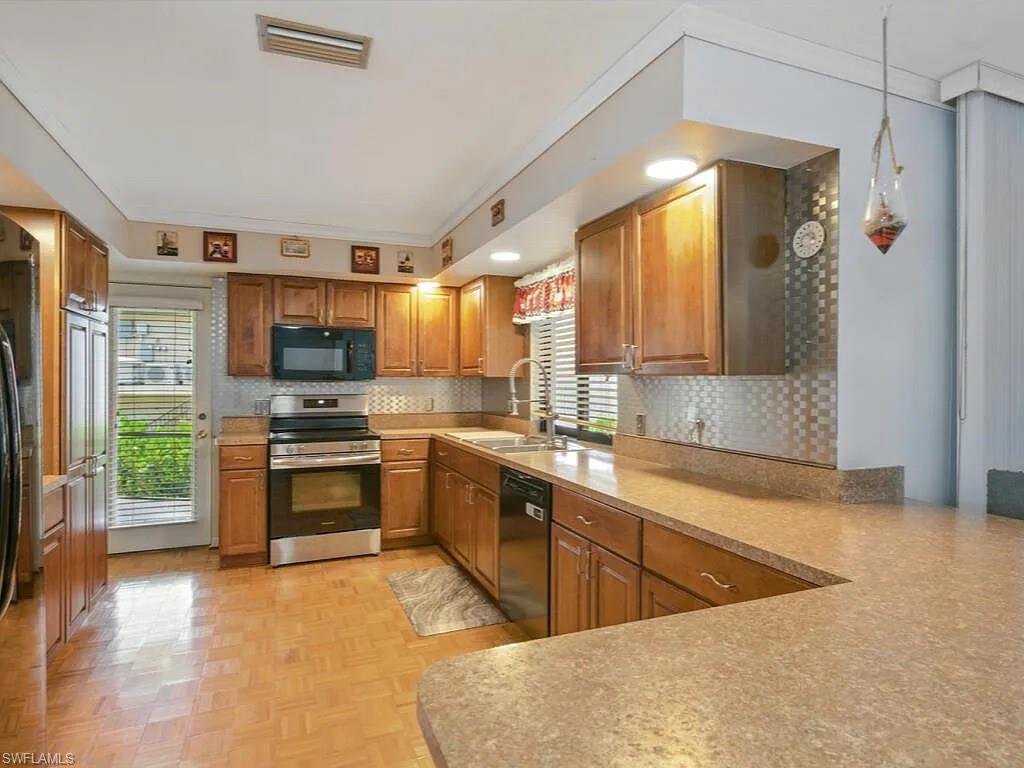 Kitchen with wood cabinets, stainless-steel appliances, and a long peninsula breakfast bar.