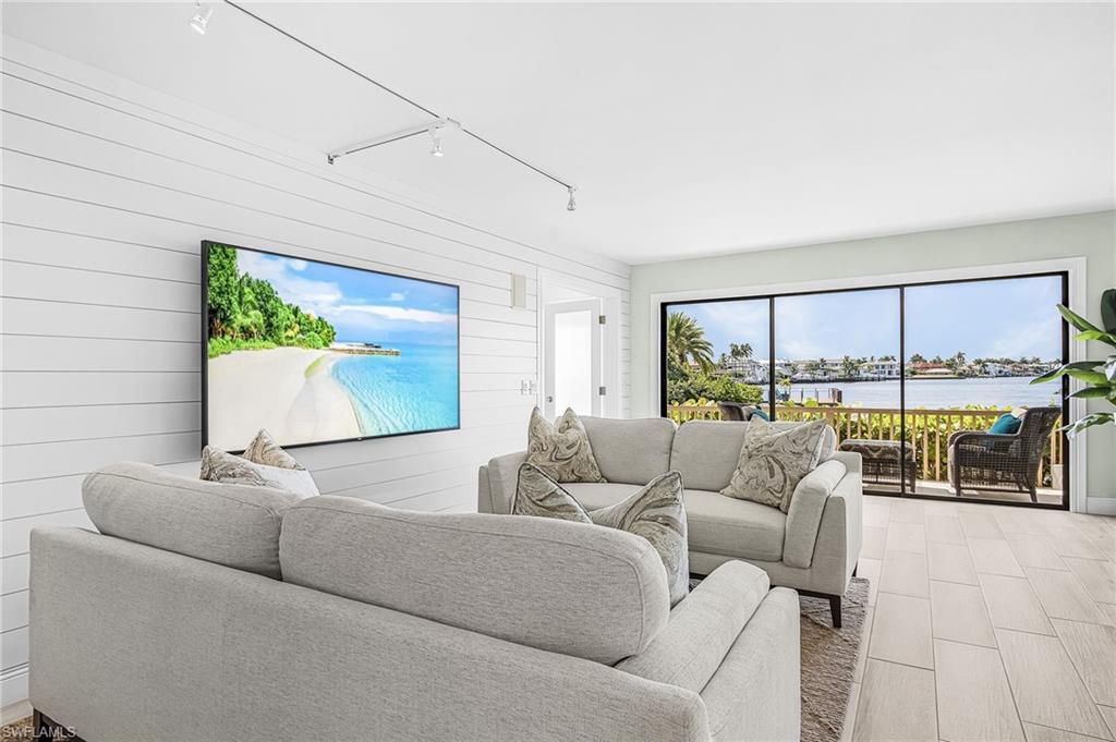 Living room with light sofas and sliding doors overlooking the water.