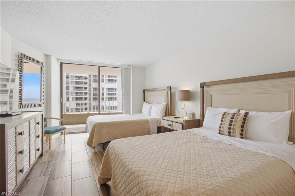 Bedroom with two beds and sliding glass doors opening to a balcony.
