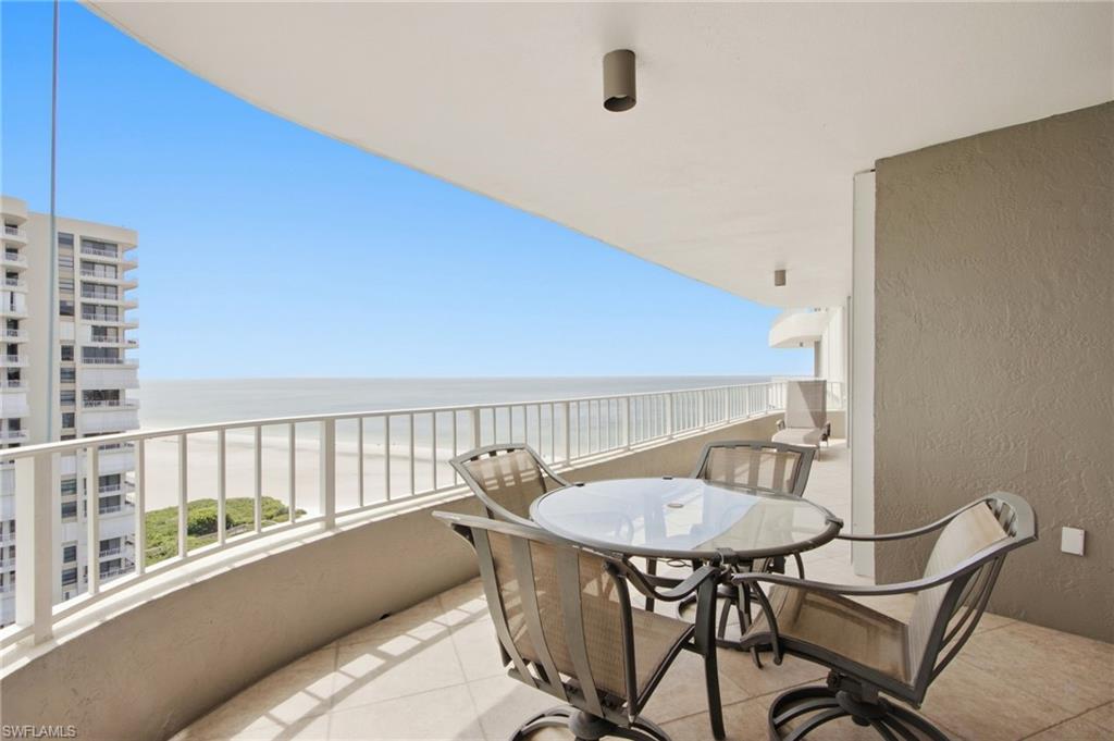 Furnished balcony with ocean views and a glass-top outdoor dining table.