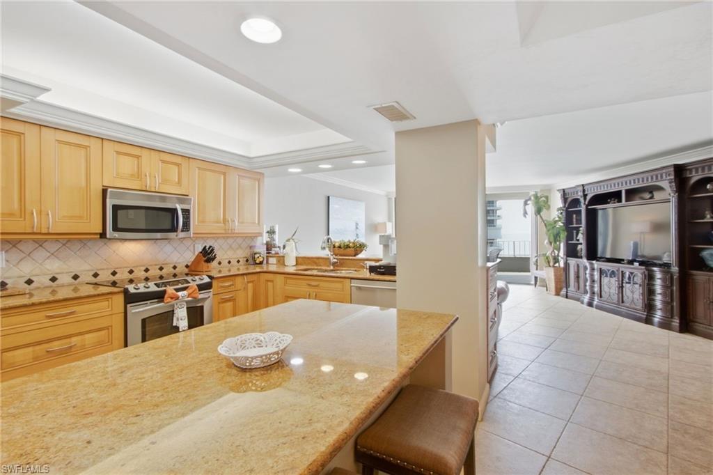 Kitchen with a granite island, honey-toned cabinets, and an open view into the living area.