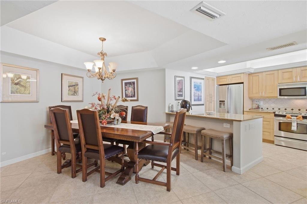 Dining room with dark wood table and chairs beside an open kitchen with a granite breakfast bar.