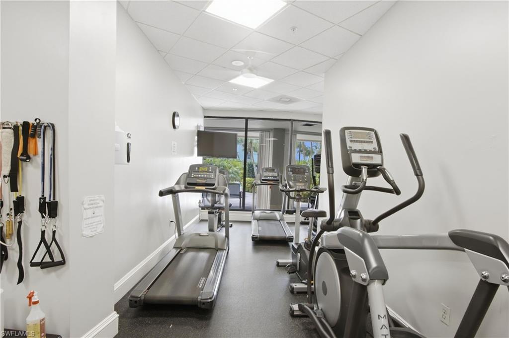 Fitness room with treadmills and stationary bikes beside glass doors overlooking greenery.