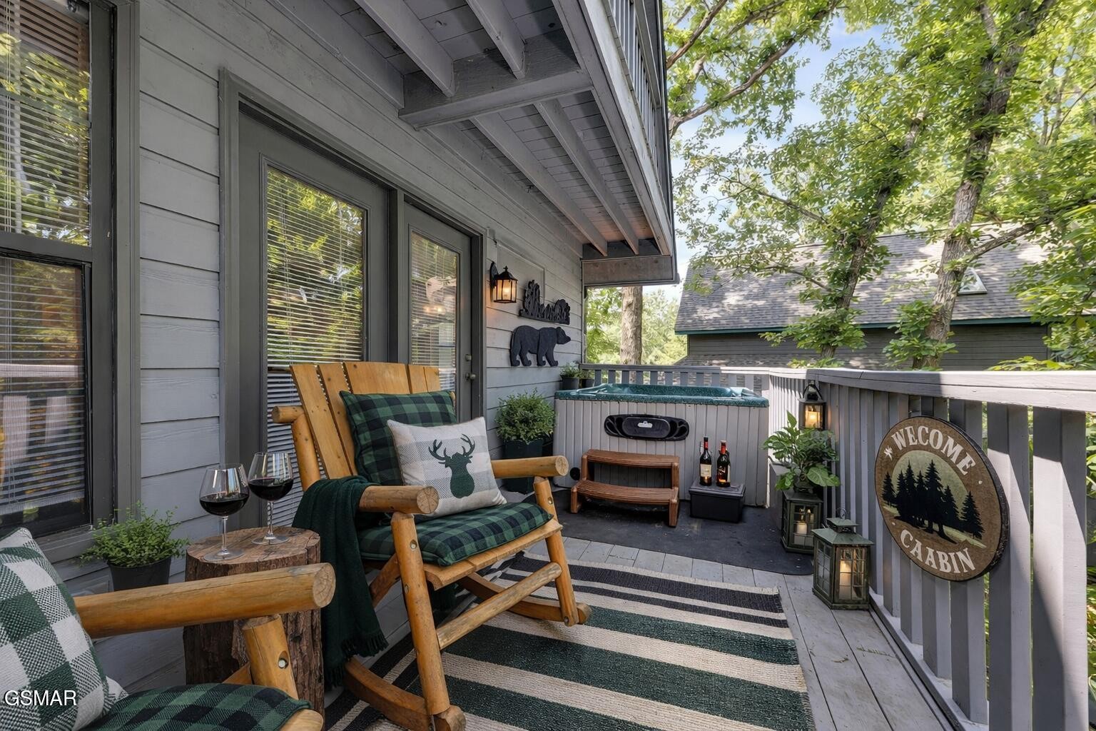 Cabin deck with plaid rocking chairs, a striped rug, and a hot tub.