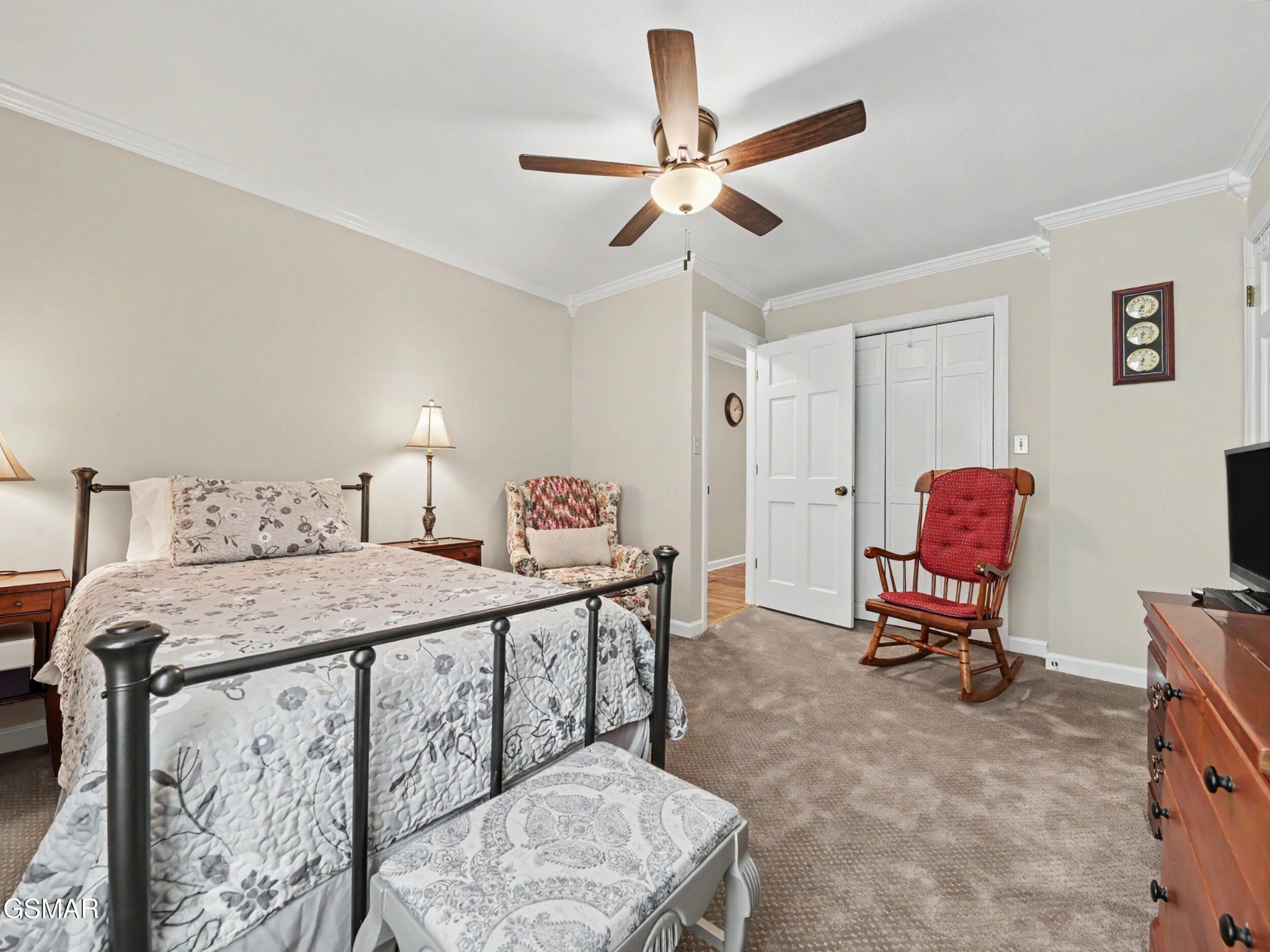 Furnished bedroom with a metal four-poster bed, patterned bedding, and a red wooden rocking chair.