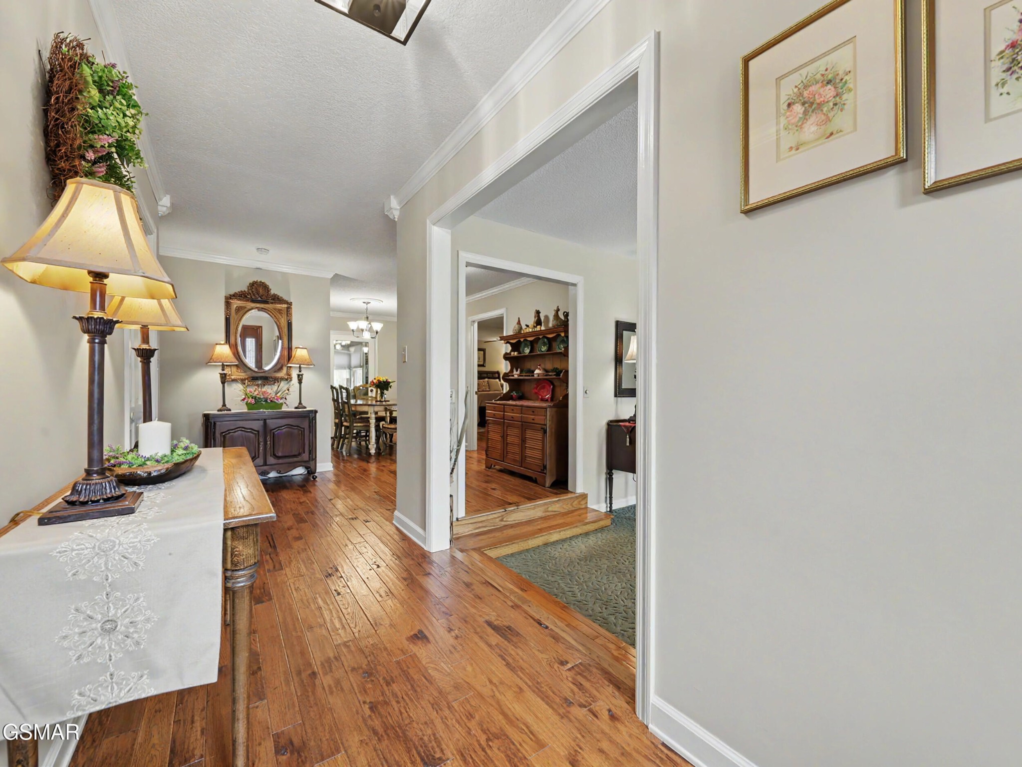 Foyer with polished hardwood floors, a console table and mirror, and doorways to adjoining rooms.