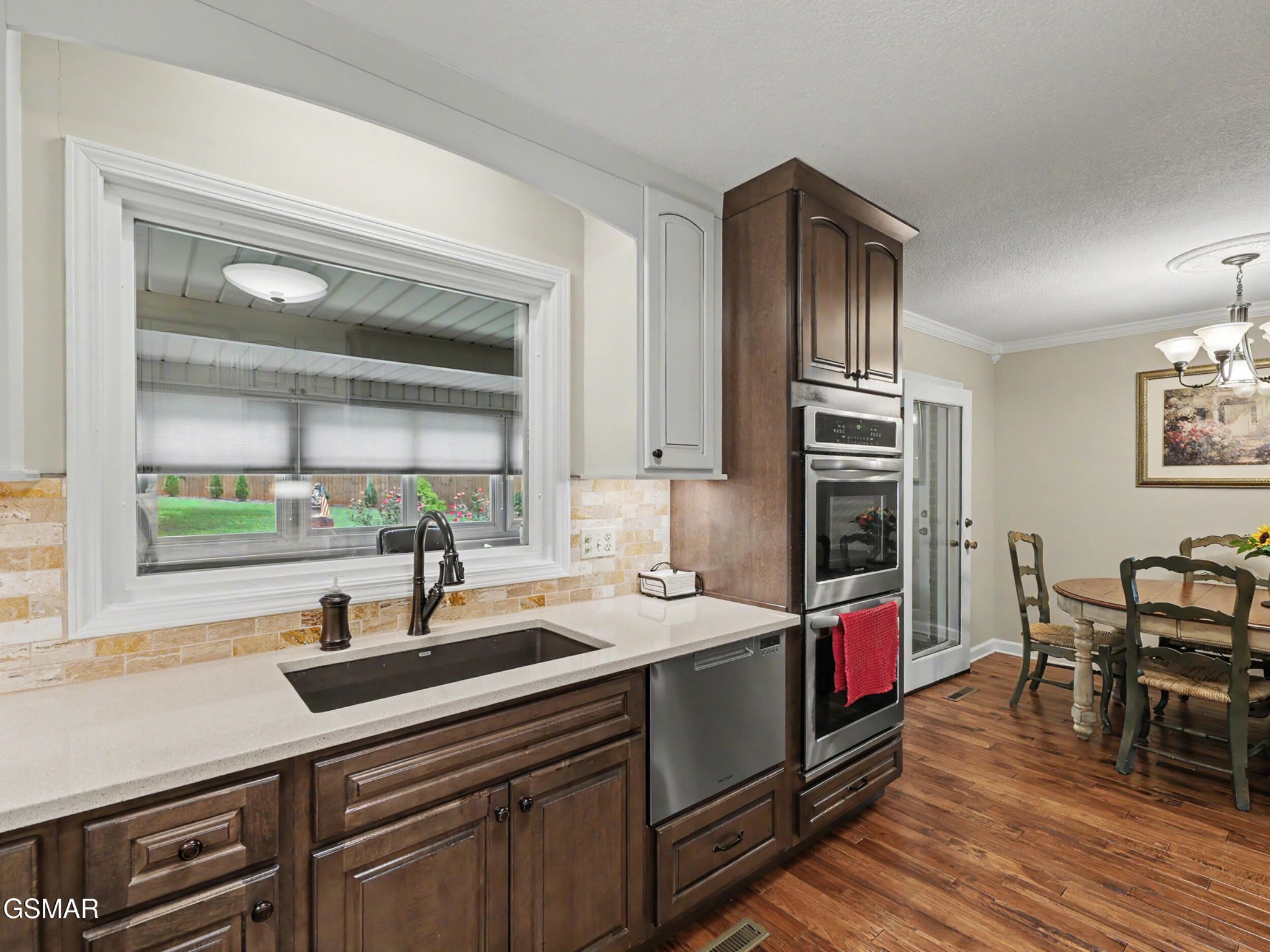 Kitchen with dark wood cabinetry, stainless steel appliances, and a dining area.
