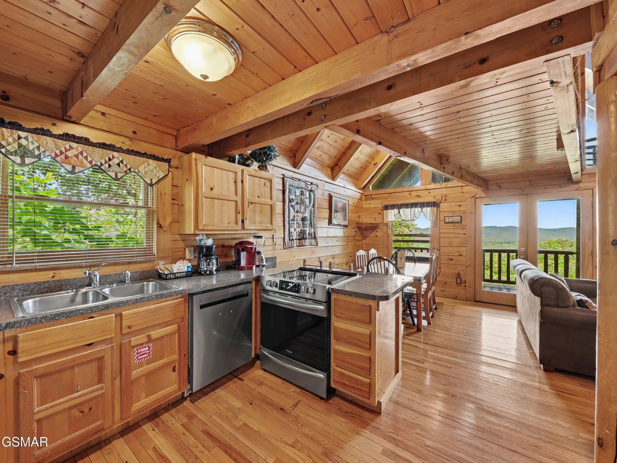 Wood-paneled cabin kitchen with a central island and mountain views through glass doors.