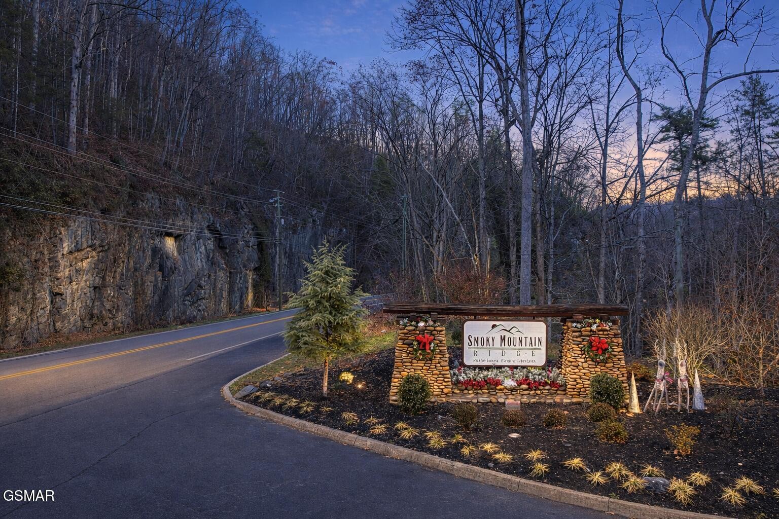 Smoky Mountain Ridge entrance sign with stone pillars and flower planters at dusk.