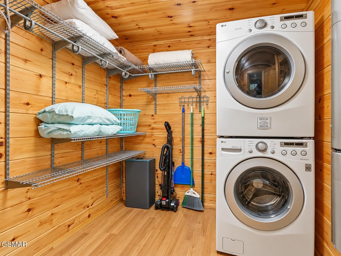 Wood-paneled laundry room with stacked washer and dryer and extensive wire storage shelving.