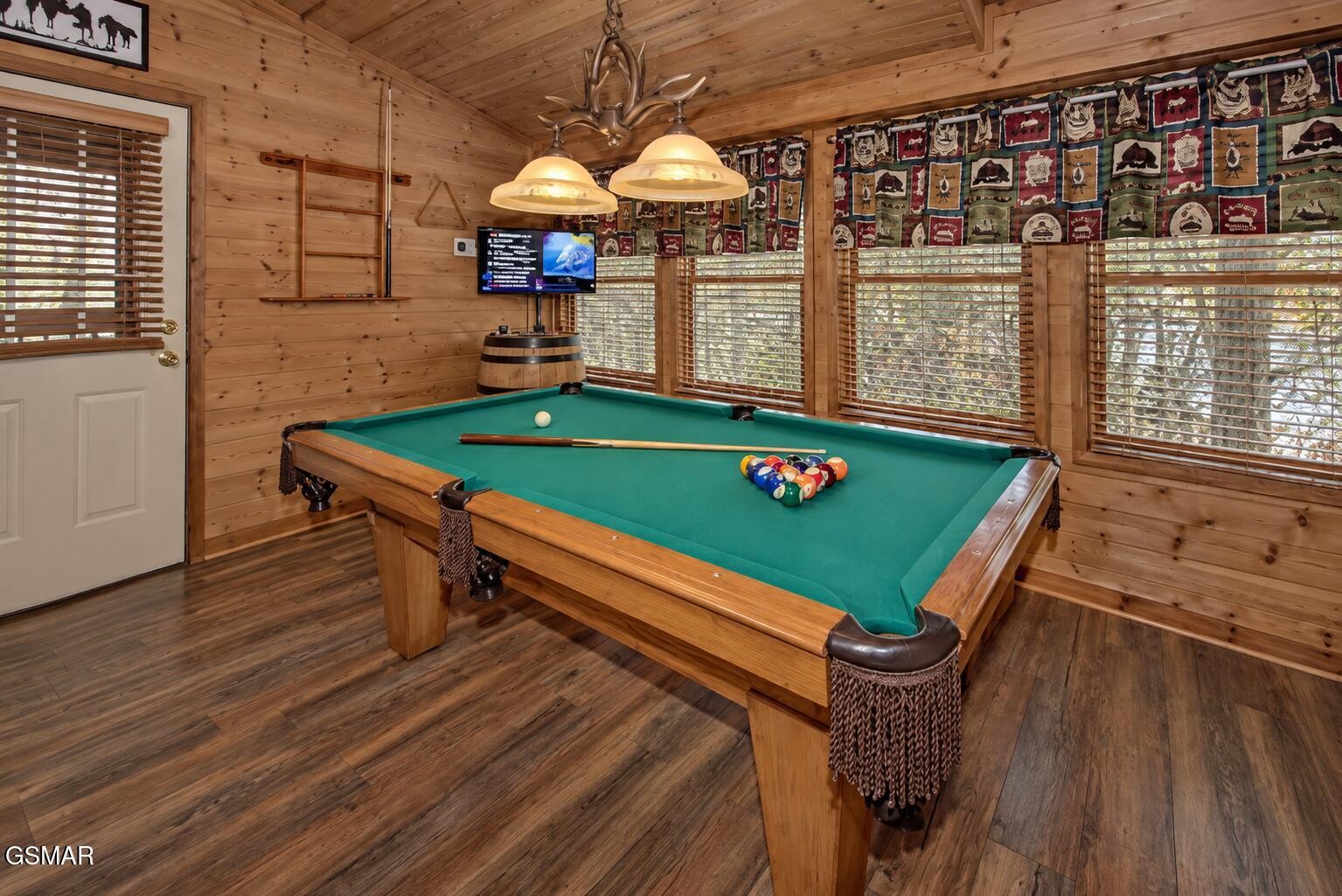 Game room with a green-felt pool table, wood-paneled walls, and wide windows with blinds.