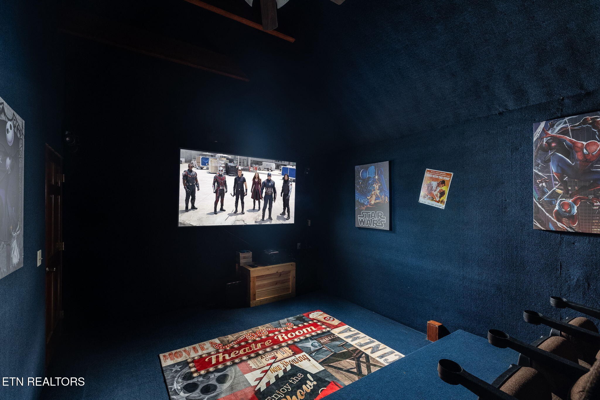 Home theater with blue walls, a movie screen, theater seating, and movie-themed decor.