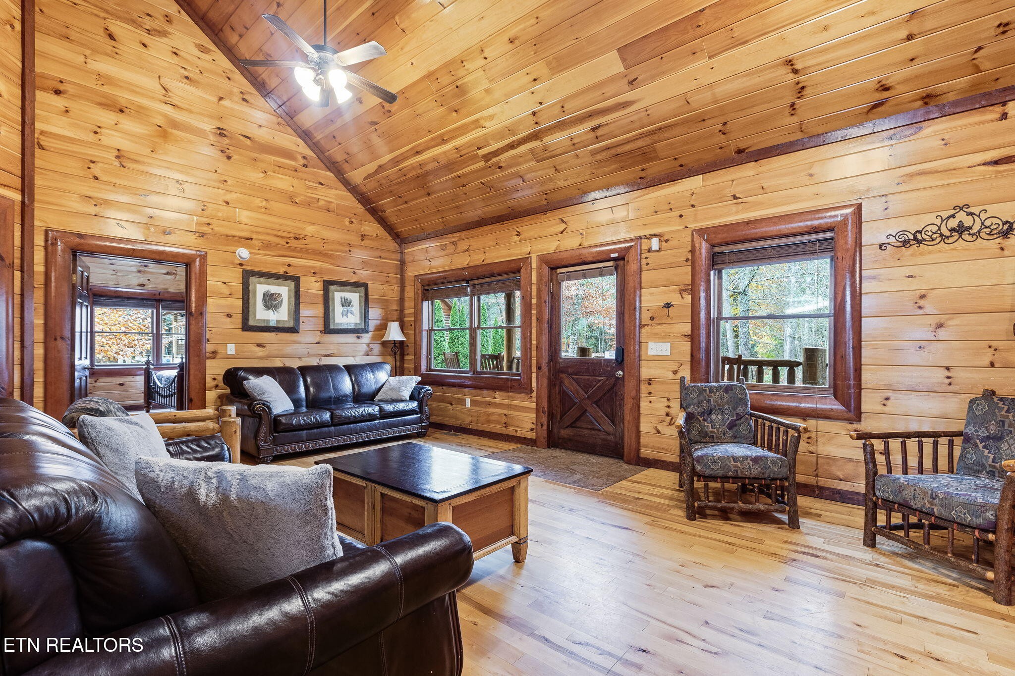 Cabin living room with vaulted wood ceiling, leather sofas, and patterned armchairs.