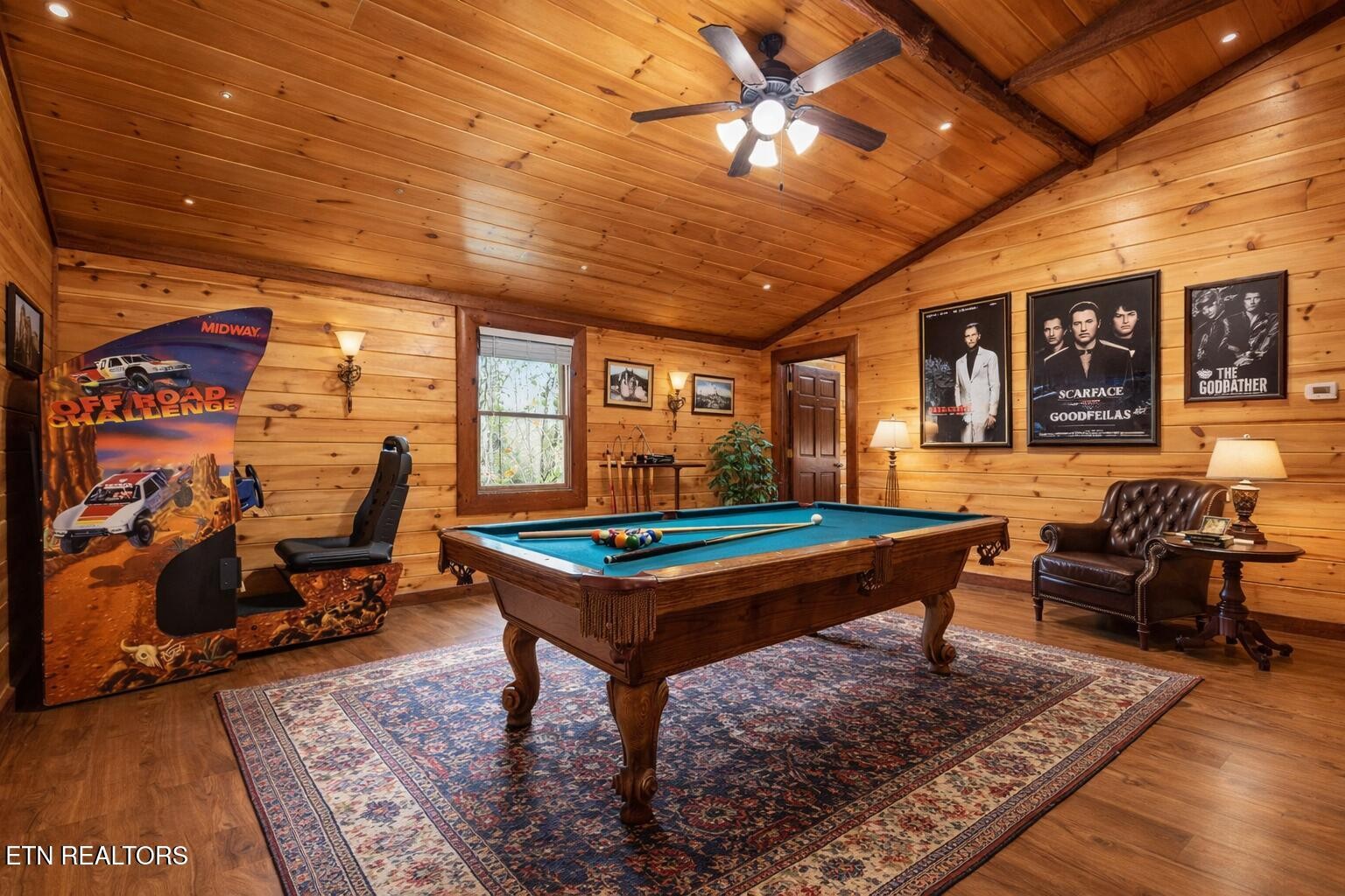 Game room with a pool table, wood-paneled walls, an arcade cabinet, and movie posters.