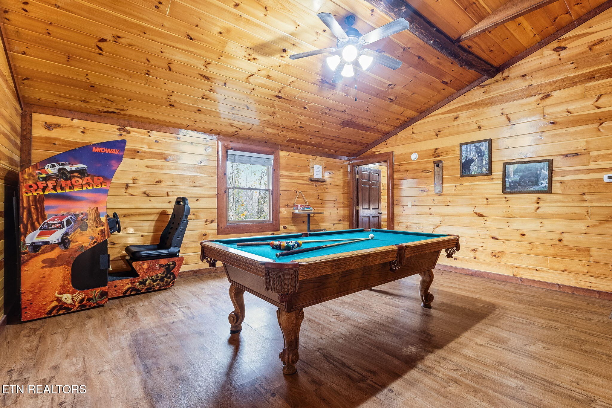 Cabin game room with a pool table, off-road racing arcade cabinet, and vaulted wood ceiling.