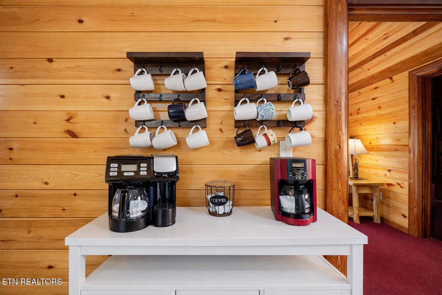 Cabin coffee station with two coffee makers and rows of hanging mugs.