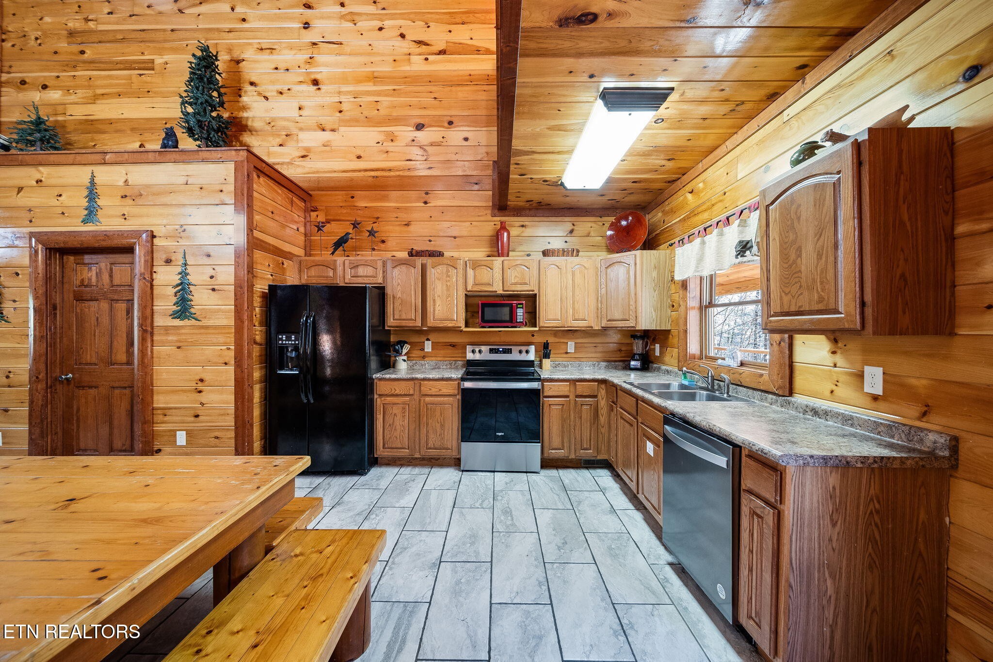 Rustic cabin kitchen with knotty pine walls, wood cabinets, and a built-in dining table with benches.