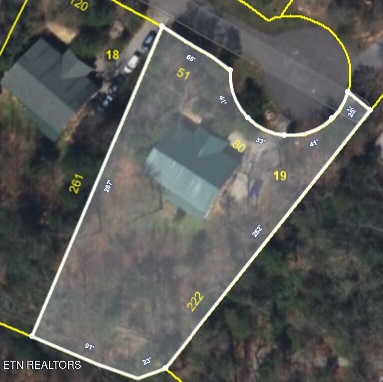 Aerial parcel map showing a house on a wooded lot with outlined property boundaries.