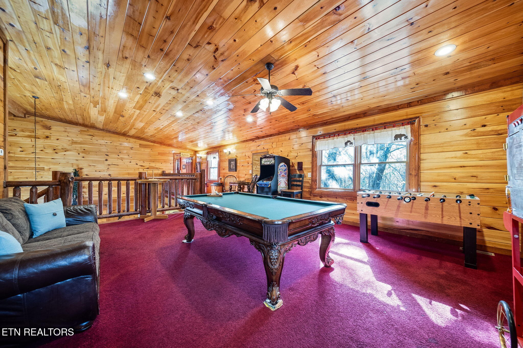Cabin game room with a pool table, foosball table, arcade cabinet, and burgundy carpet