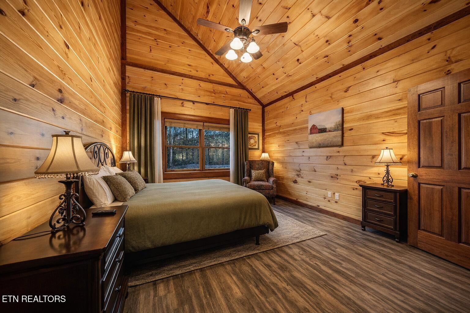 Furnished bedroom with a vaulted wood ceiling, plank walls, and a large bed.