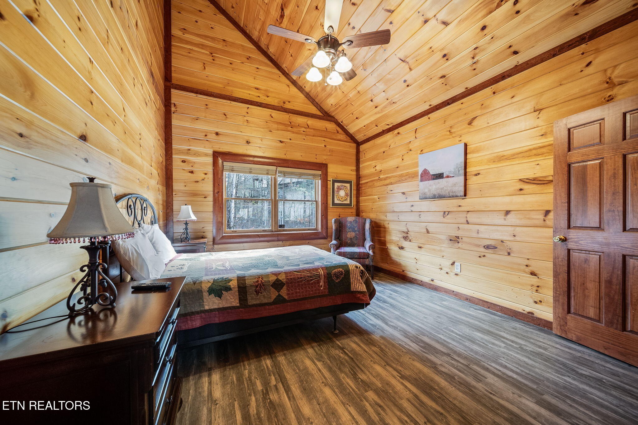 Cabin bedroom with a patchwork-quilt bed and vaulted wood-plank ceiling.
