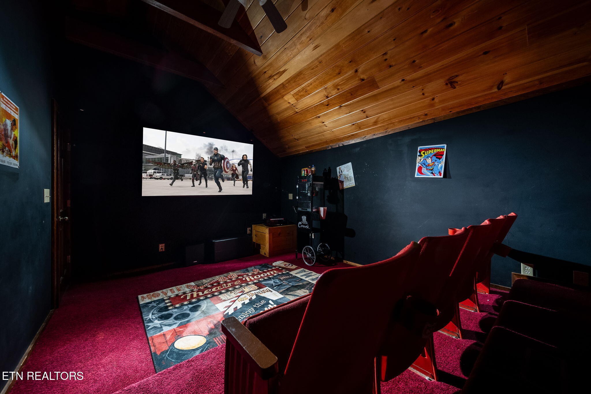 Home theater with red cinema seats, a large screen, and a vaulted wood ceiling.