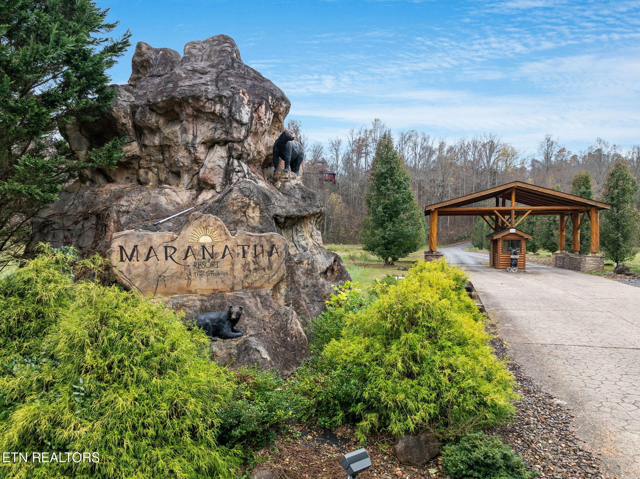 Maranatha Resort entrance with a carved rock sign, bear statues, and a timber-covered gate.