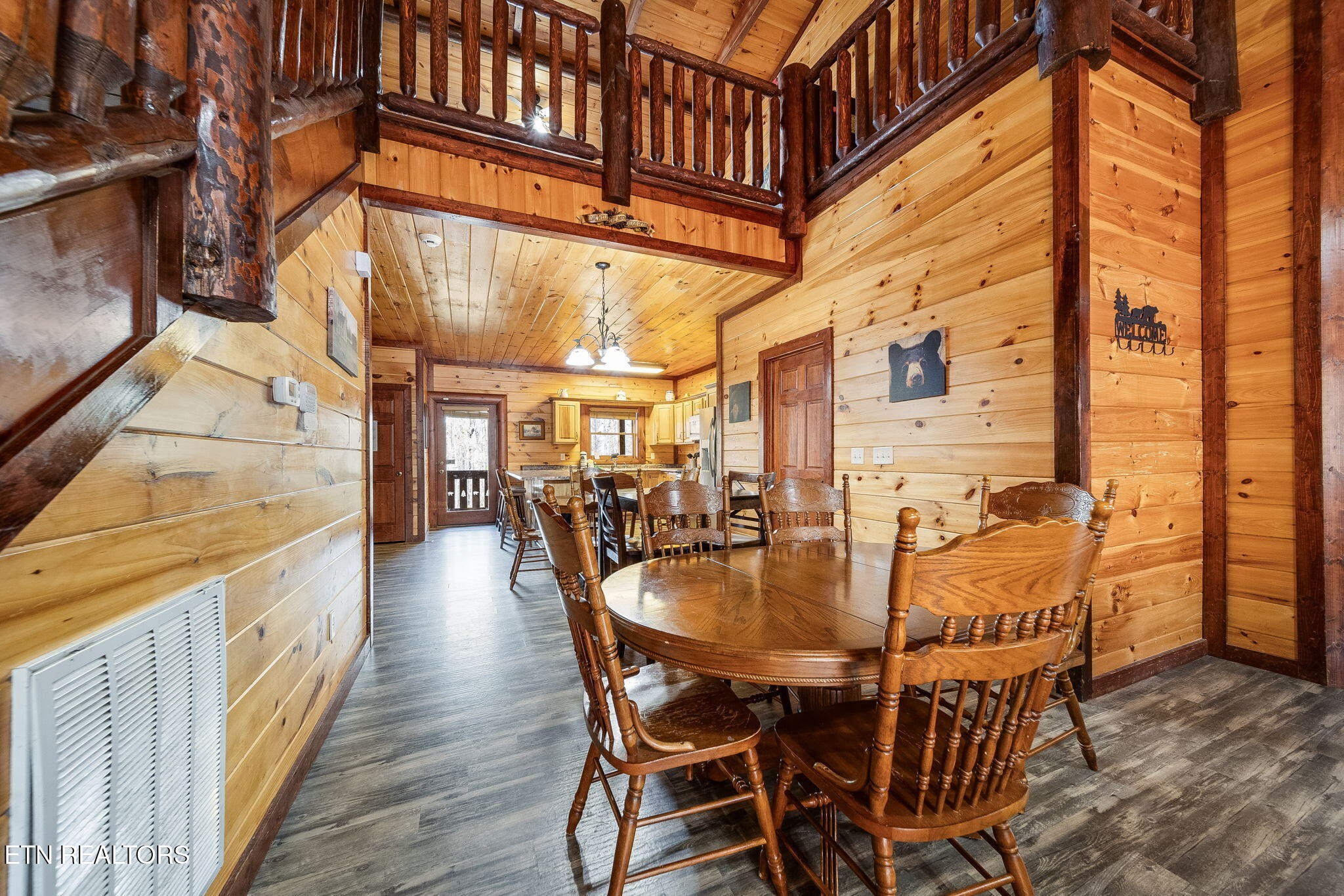 Cabin dining area with a round wooden table beneath a timber-railed loft.