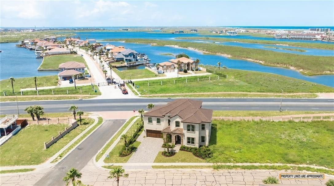 Aerial view of a two-story home beside a road, with waterways and homes beyond.