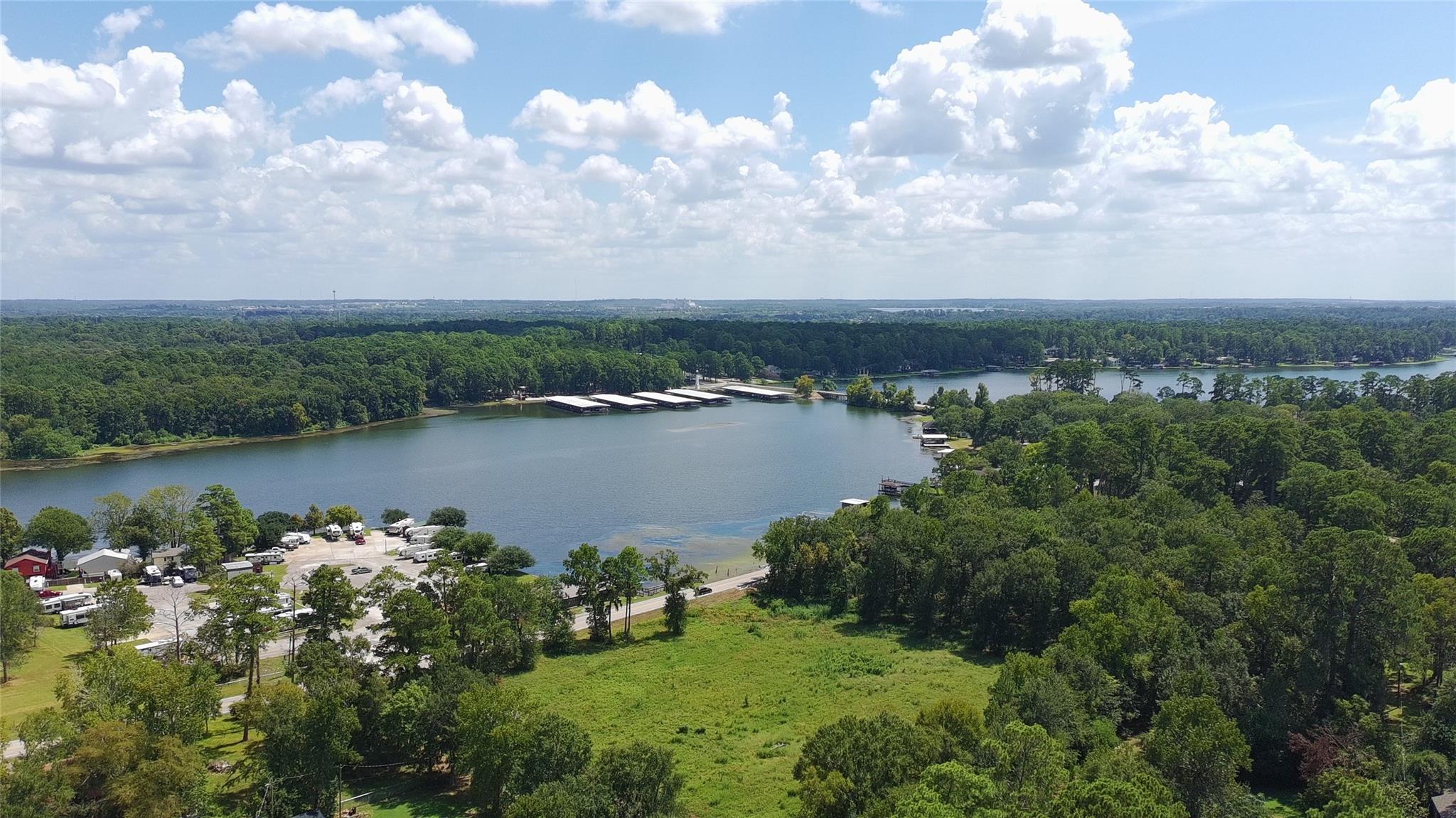 Aerial view of a wooded lake with shoreline docks and a campground in the foreground.