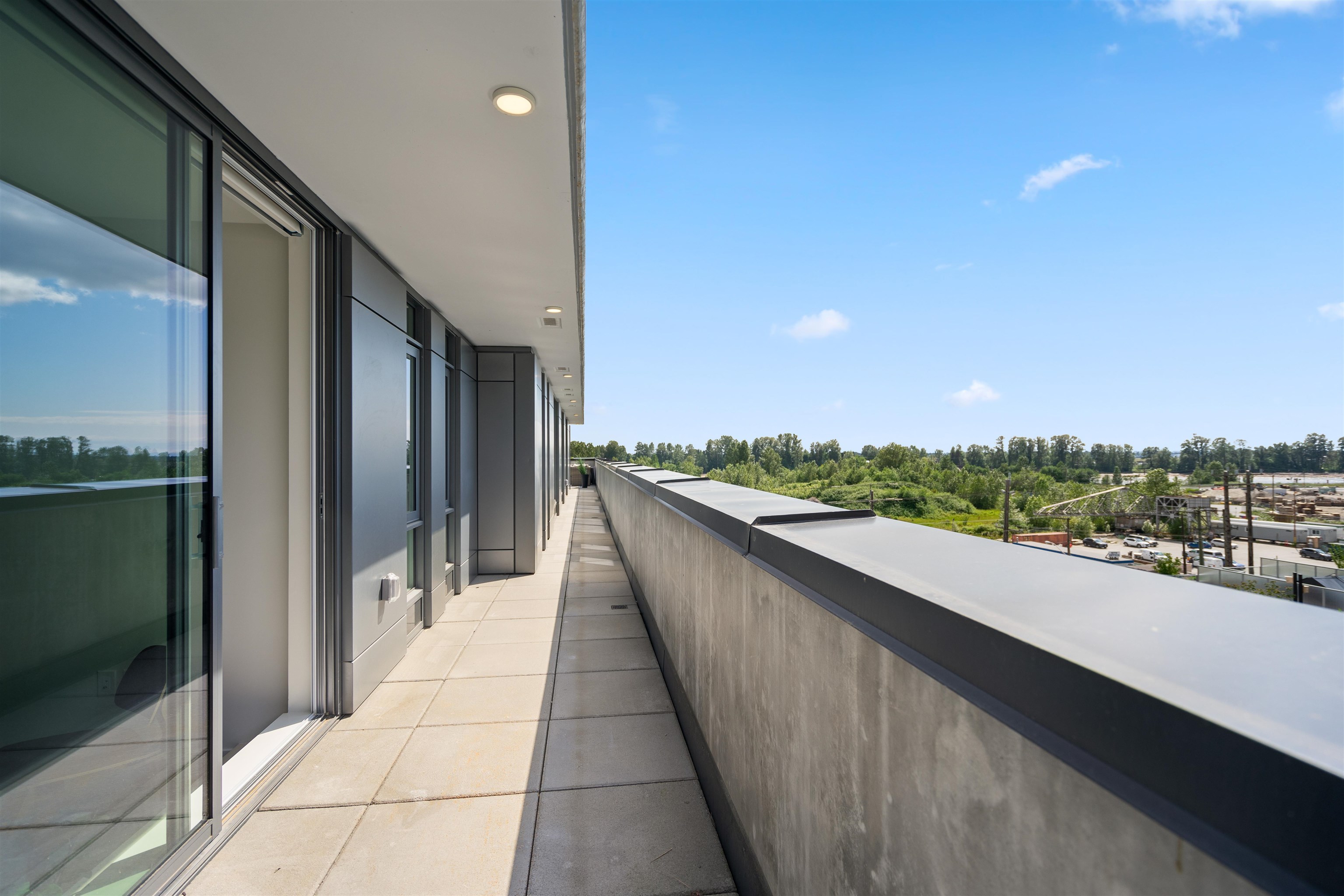 Apartment balcony with sliding glass doors and views over greenery.