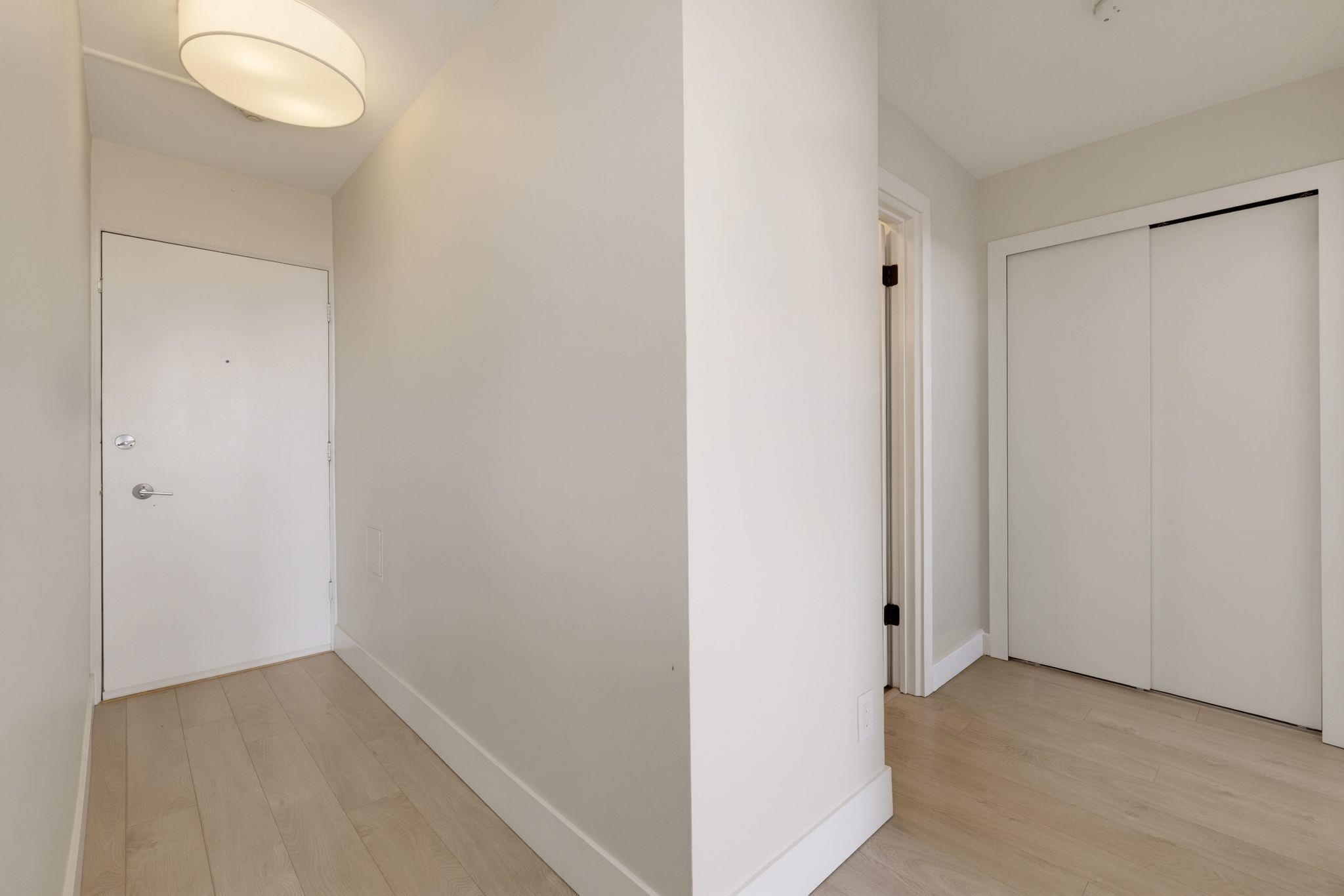 Apartment entryway with a white front door and sliding closet doors.