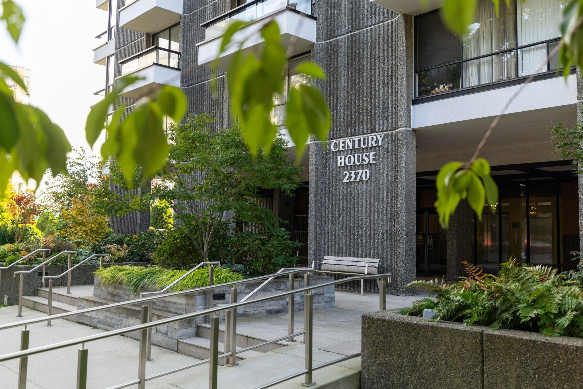 Century House apartment entrance with landscaped planters, concrete facade, and railed walkway.