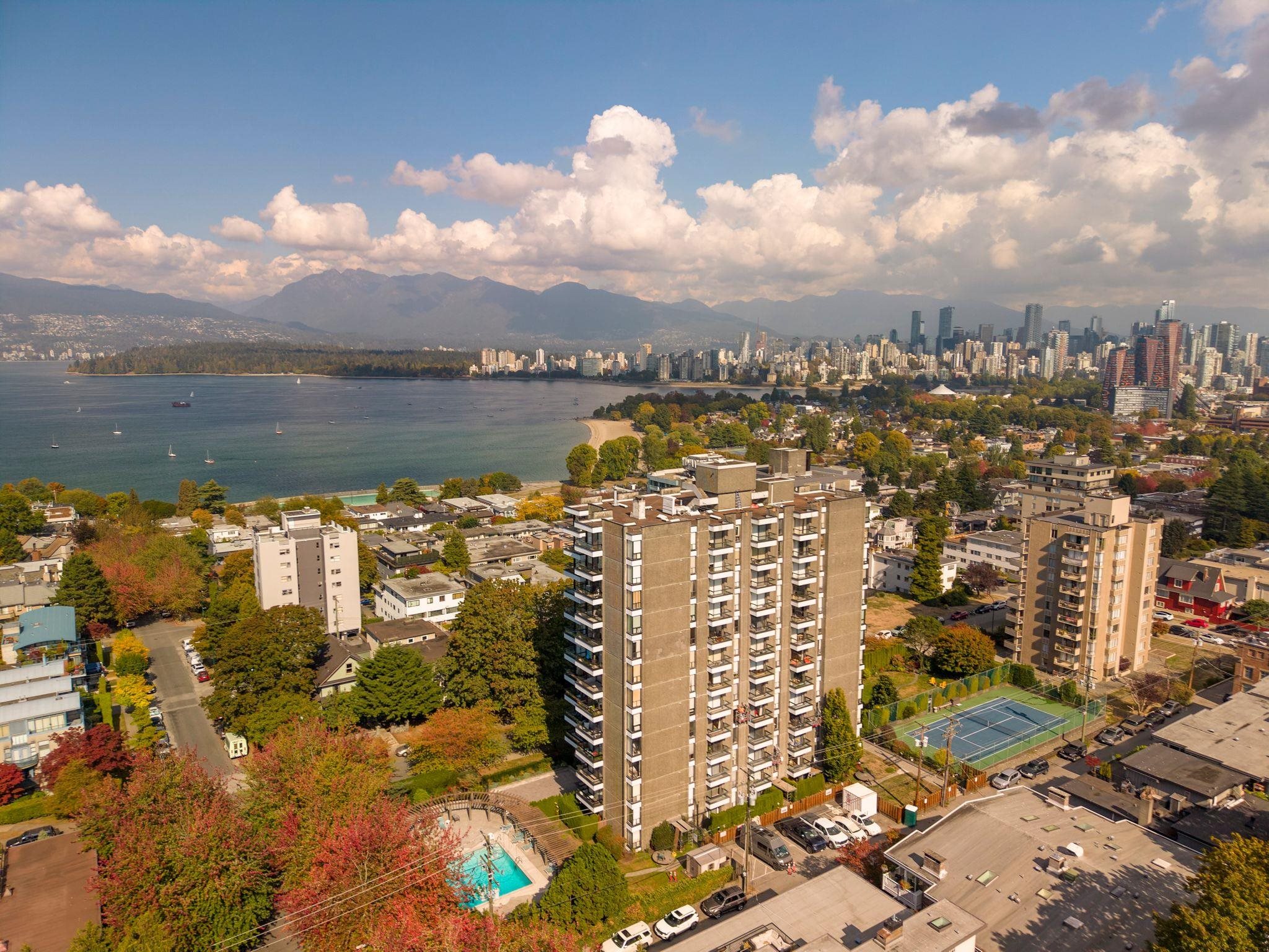 Vancouver condominium tower overlooking English Bay, with a tennis court and pool nearby.