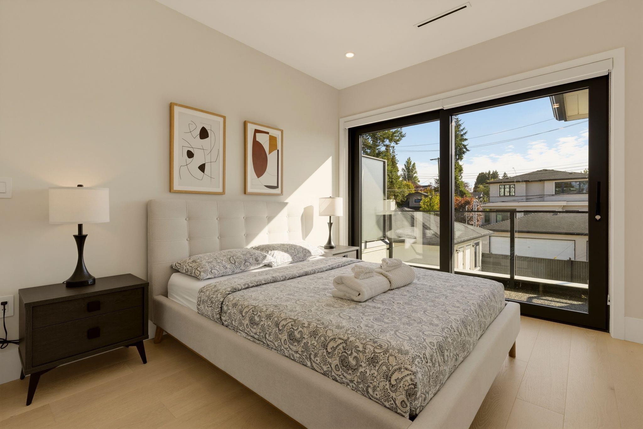 Furnished bedroom with a large upholstered bed and sliding glass doors opening onto a balcony.