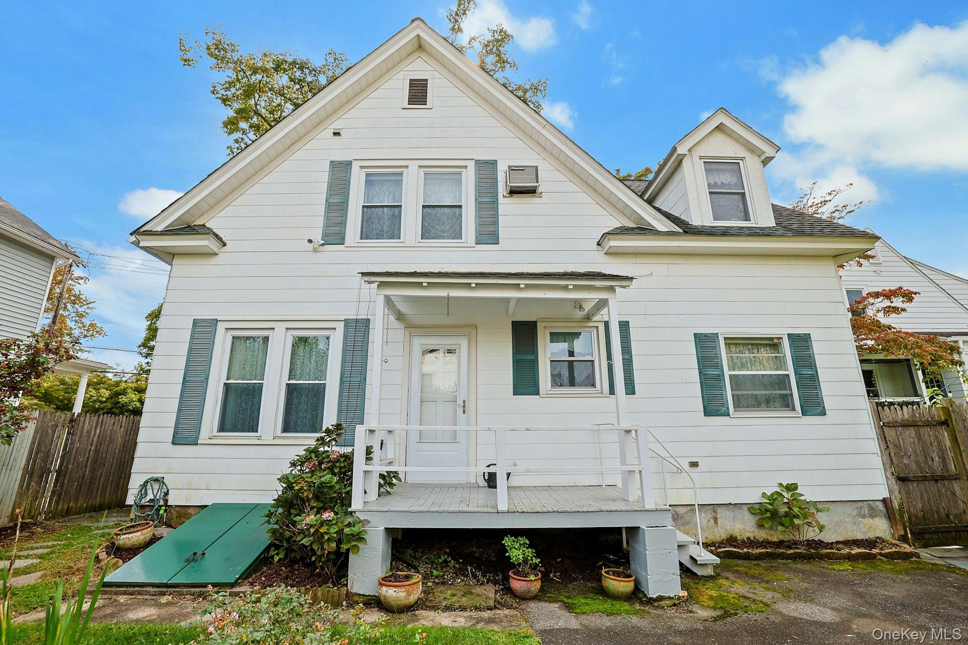 White two-story house with teal shutters and a small covered front porch.