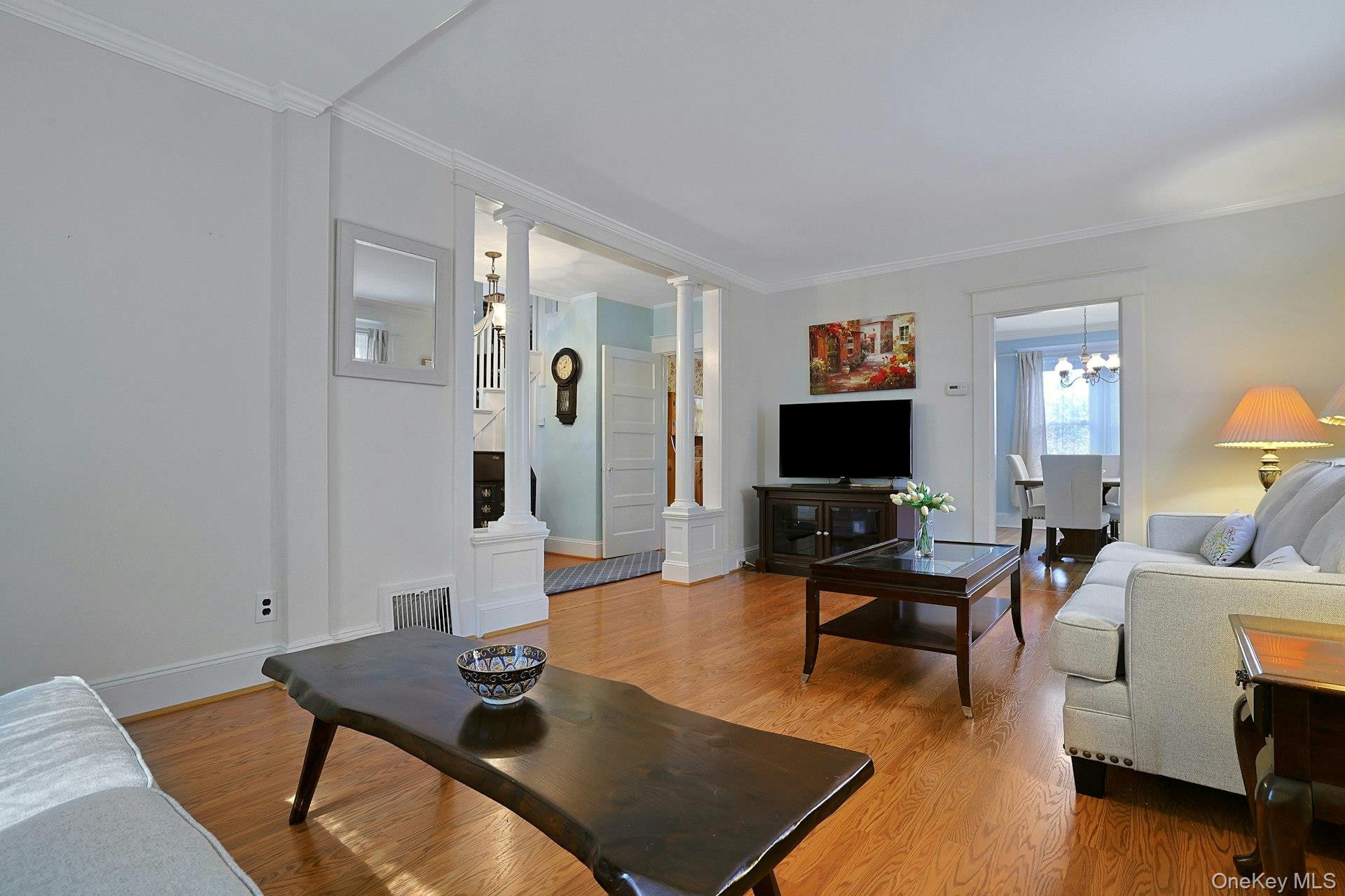 Living room with hardwood floors, white columns, and a view into the dining room.