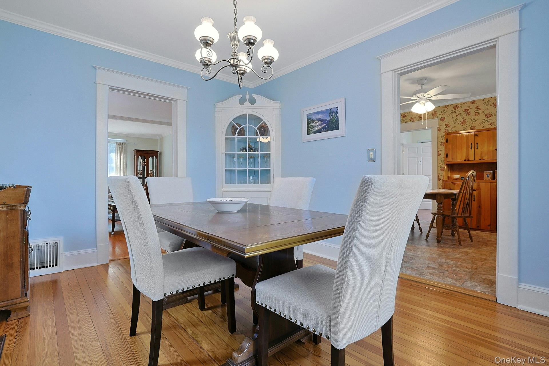 Dining room with a wood table, upholstered chairs, hardwood floors, and a built-in glass-front cabinet.