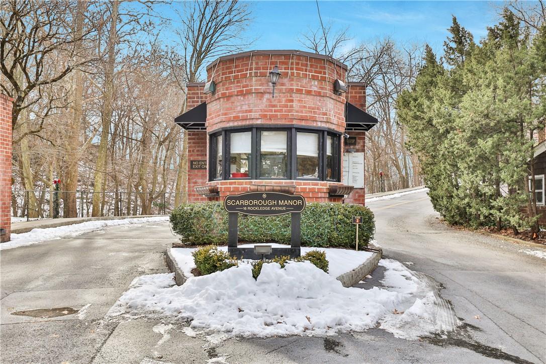 Scarborough Manor’s round brick gatehouse and entrance sign between snow-lined driveways.