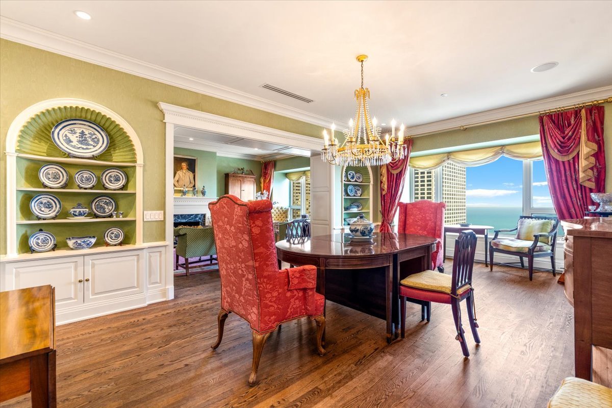 Dining room with red chairs, built-in display shelves, and windows overlooking Lake Michigan.