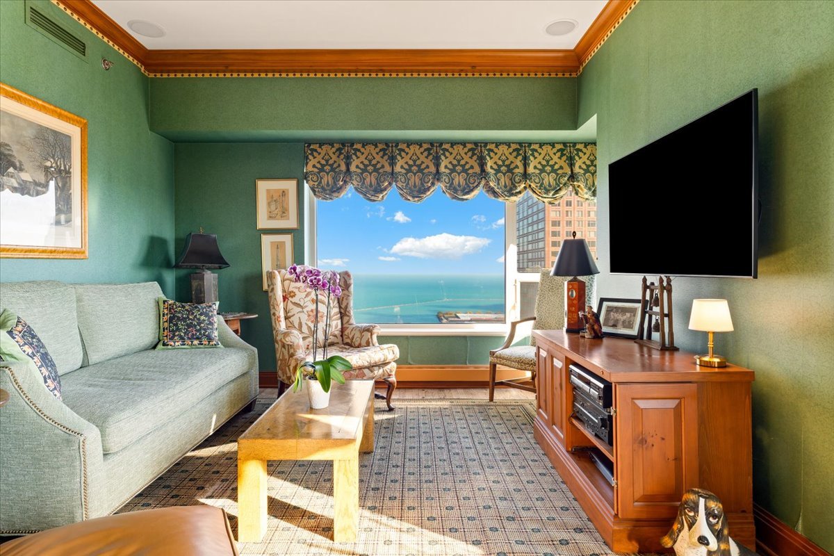 Living room with green walls and lake and city views through a large window.