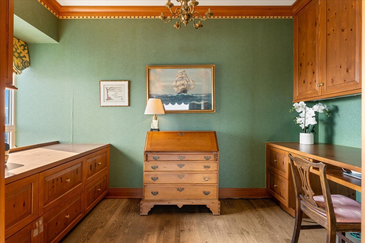 Furnished study with green walls, extensive wood cabinetry, and a central secretary desk.
