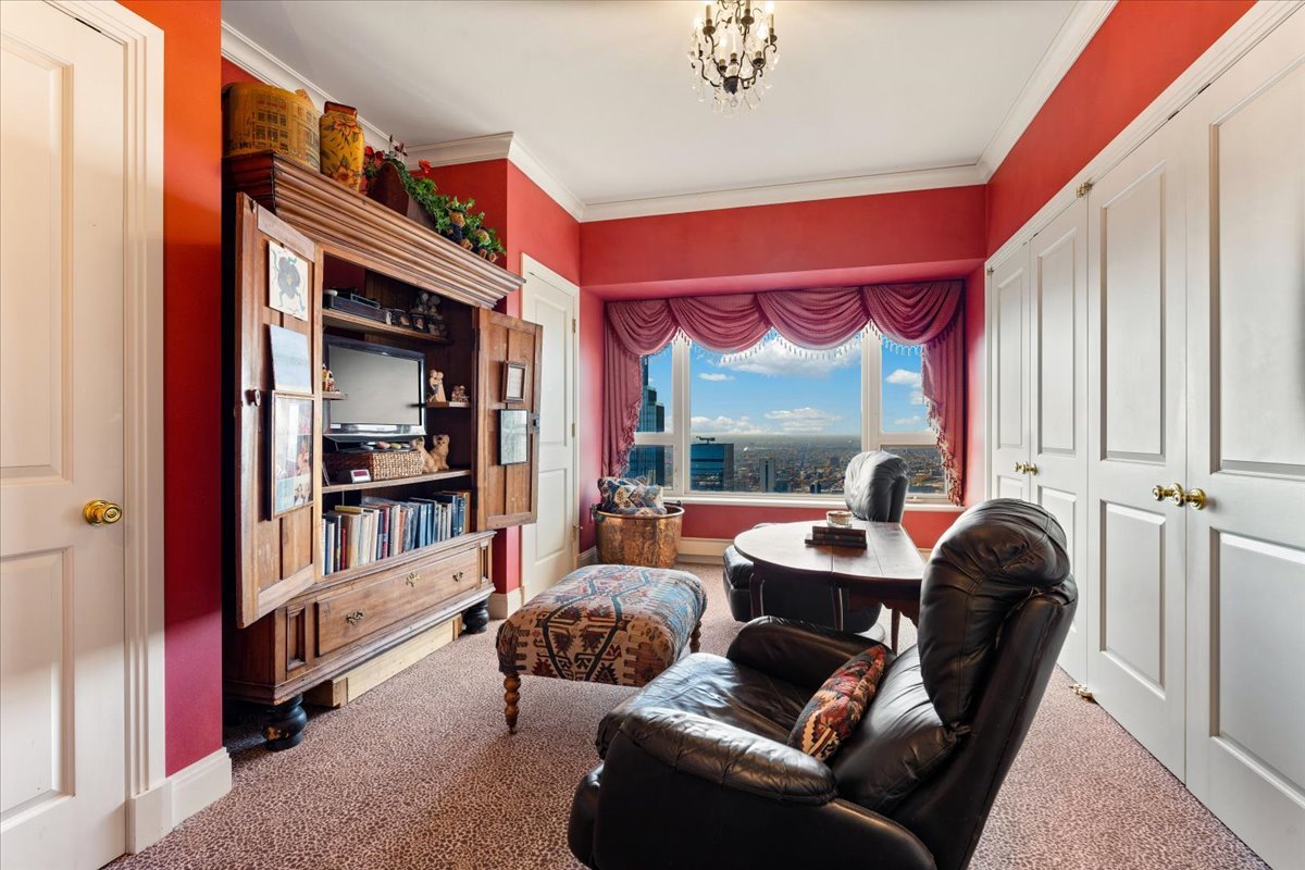 Furnished den with red walls, leather recliners, and a large window overlooking the skyline.