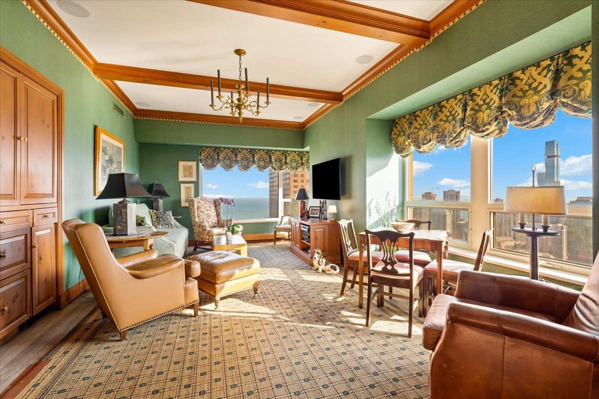 Furnished living room with green walls, leather seating, and windows overlooking Lake Michigan and Chicago.